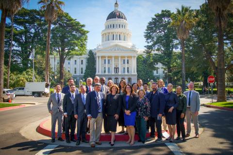 Group of people in front of a white-domed building with palm trees.
